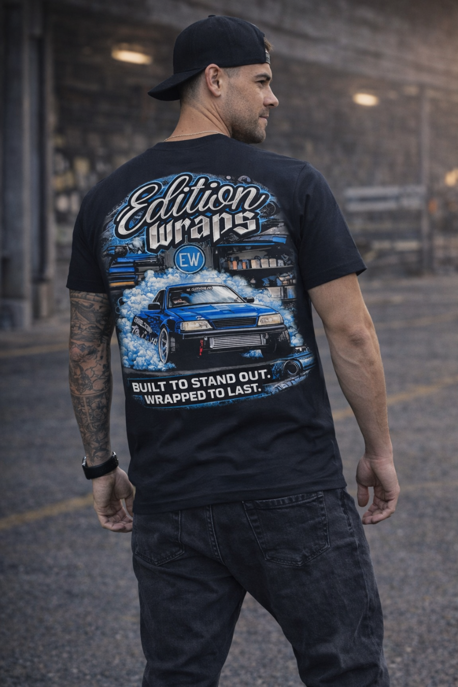 Man wearing a black t-shirt with 'Edition Wraps' graphic design in an urban setting.