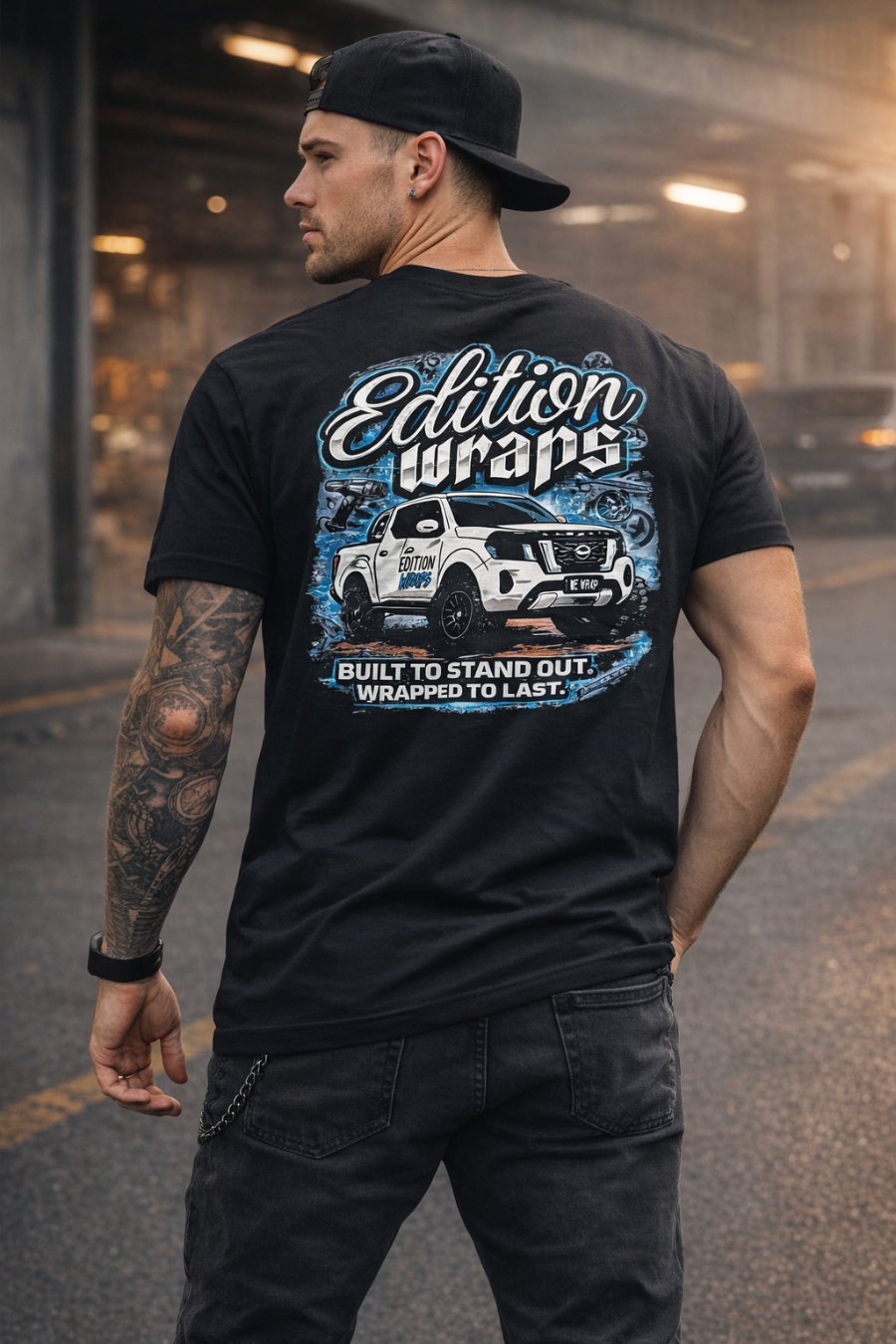Person wearing a black t-shirt with 'Edition Wraps' graphic design outdoors.